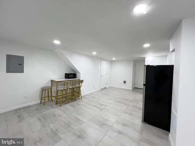 basement featuring stainless steel fridge, bar, and electric panel