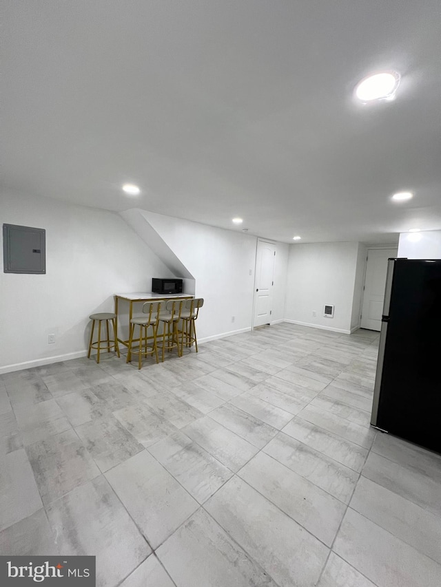 basement with electric panel and stainless steel refrigerator