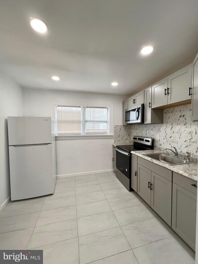 kitchen featuring appliances with stainless steel finishes, gray cabinetry, tasteful backsplash, and sink