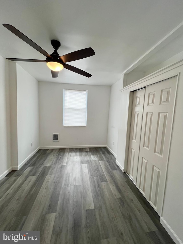 unfurnished bedroom with ceiling fan, a closet, and dark hardwood / wood-style flooring