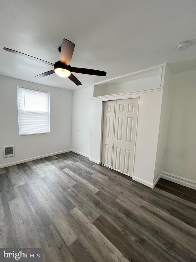 unfurnished bedroom with ceiling fan, a closet, and dark hardwood / wood-style floors