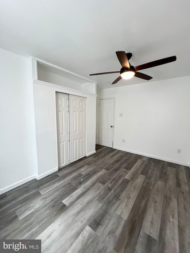 unfurnished bedroom with ceiling fan, a closet, and dark hardwood / wood-style floors