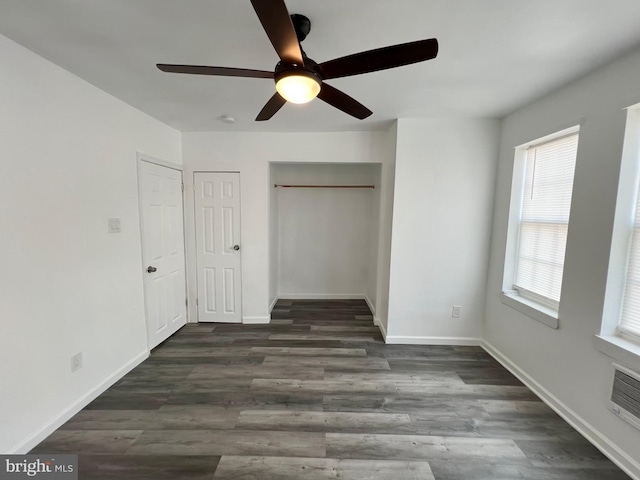 unfurnished bedroom with ceiling fan, dark wood-type flooring, and two closets