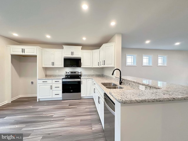 kitchen featuring kitchen peninsula, stainless steel appliances, light stone countertops, white cabinets, and sink