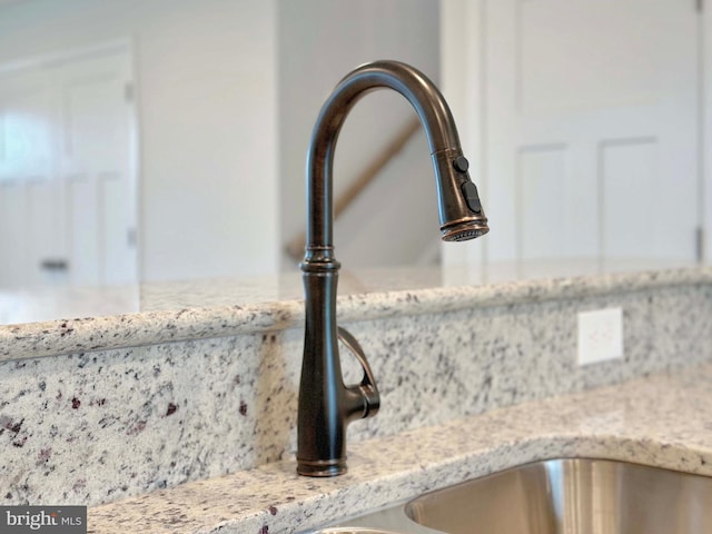 interior details with light stone countertops, sink, and decorative backsplash