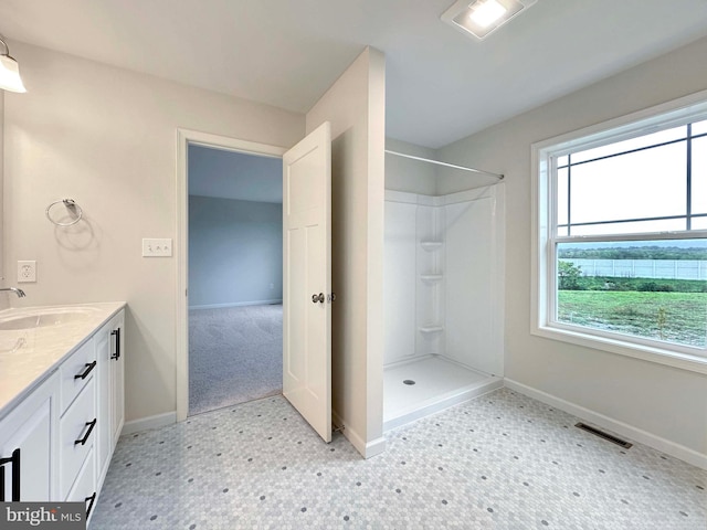 bathroom featuring walk in shower, vanity, and a wealth of natural light