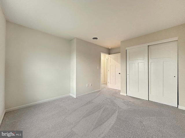 unfurnished bedroom with light carpet and a closet