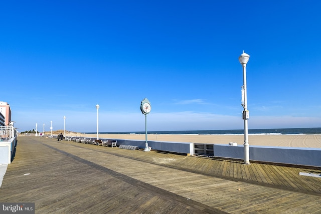 view of dock with a water view and a beach view