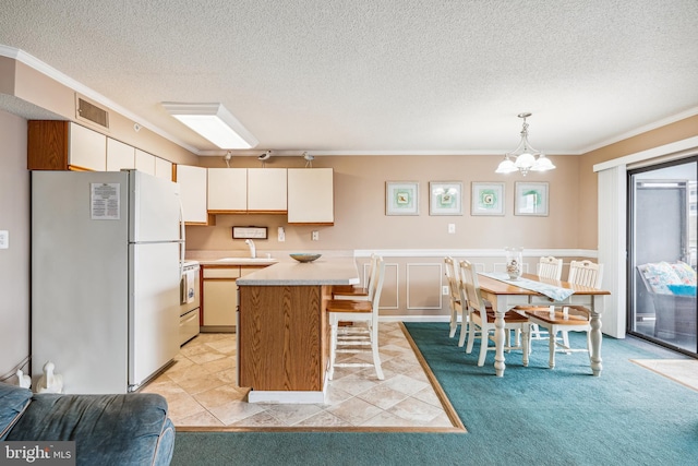 kitchen featuring electric range, fridge, decorative light fixtures, a kitchen island, and sink