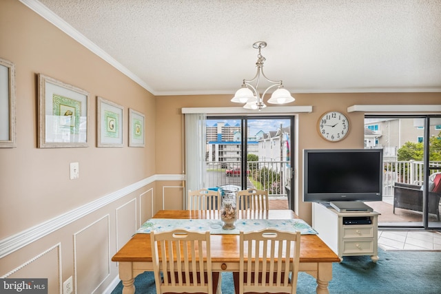 dining space featuring carpet floors, a textured ceiling, ornamental molding, and a chandelier