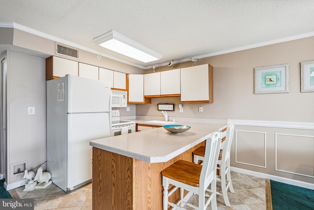 kitchen featuring sink, white appliances, a textured ceiling, and white cabinetry