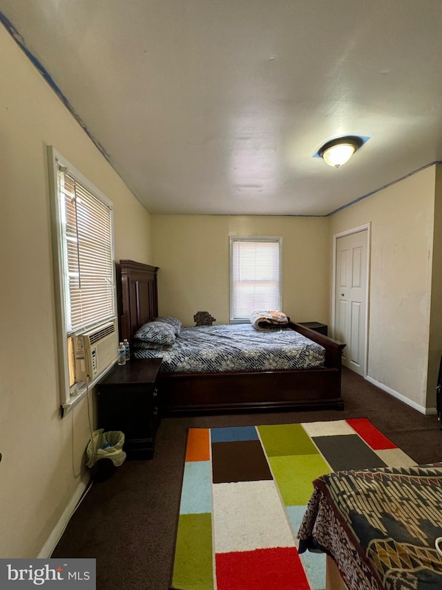 bedroom with dark colored carpet and multiple windows