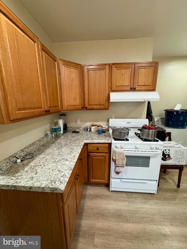 kitchen featuring light stone countertops, light hardwood / wood-style flooring, and white gas range oven