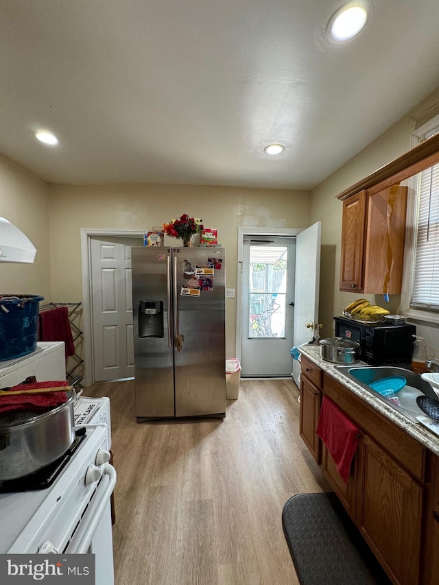 kitchen featuring sink, white electric range oven, stainless steel fridge with ice dispenser, and light wood-type flooring