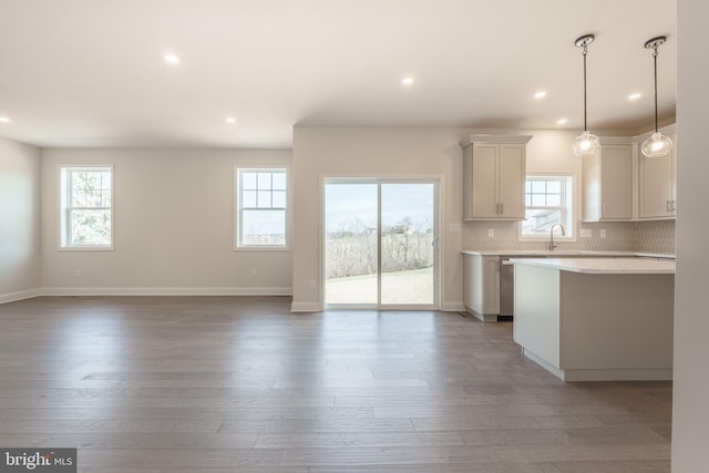 kitchen with a wealth of natural light, white cabinetry, pendant lighting, and backsplash