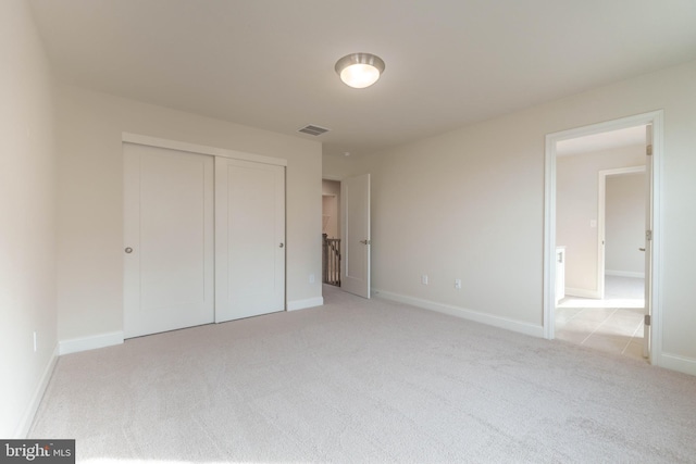 unfurnished bedroom with light carpet and a closet