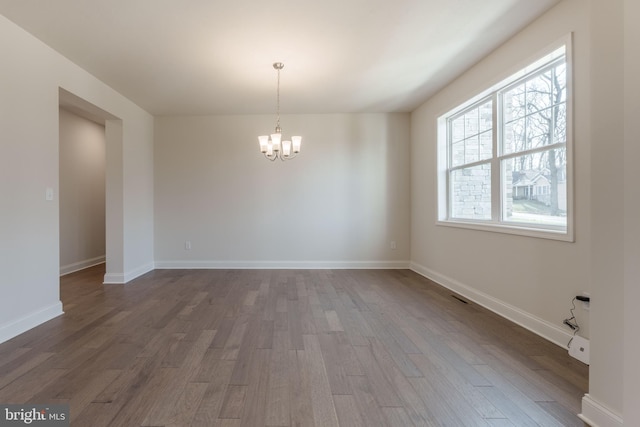 spare room featuring a chandelier and dark hardwood / wood-style floors