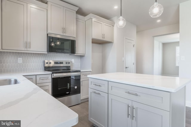 kitchen featuring backsplash, dark hardwood / wood-style floors, hanging light fixtures, stainless steel range with electric cooktop, and light stone counters