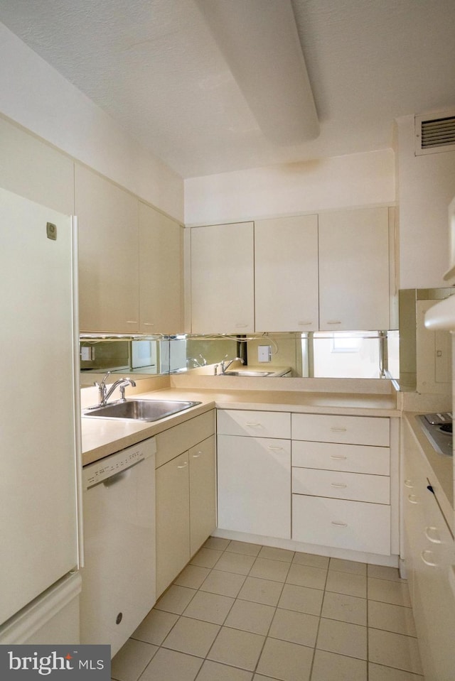 kitchen with sink, white appliances, light tile patterned floors, and white cabinets