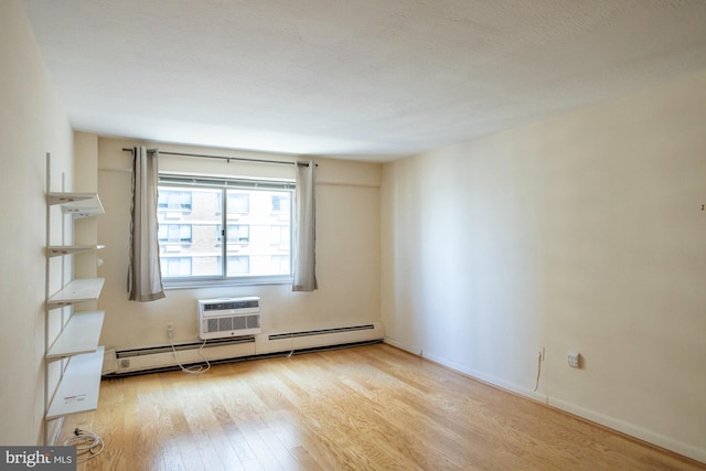 empty room featuring baseboard heating, light hardwood / wood-style flooring, and a wall unit AC