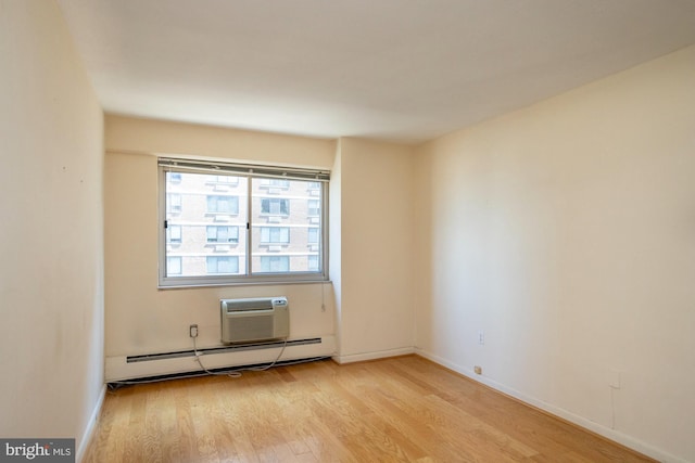 spare room with an AC wall unit, a baseboard heating unit, and light hardwood / wood-style flooring