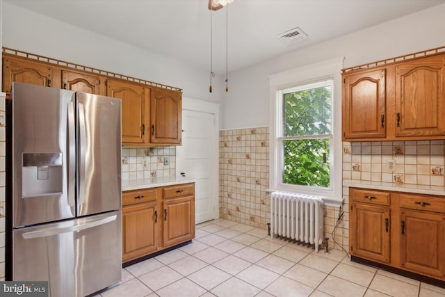 kitchen featuring stainless steel refrigerator with ice dispenser, tasteful backsplash, radiator heating unit, and light tile patterned flooring