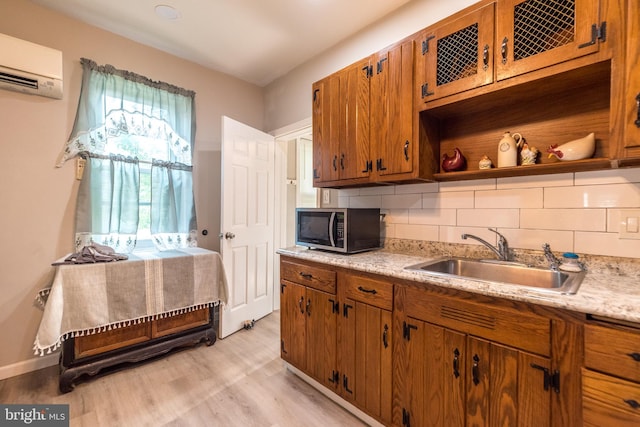 kitchen with light wood-type flooring, backsplash, sink, and an AC wall unit