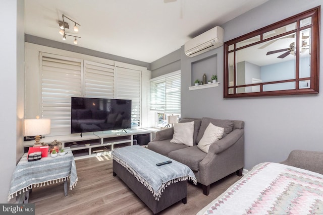 living room with ceiling fan, wood finished floors, and a wall mounted AC