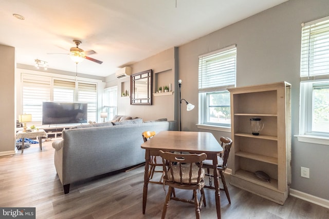 dining space with a wall unit AC, wood finished floors, a ceiling fan, and baseboards