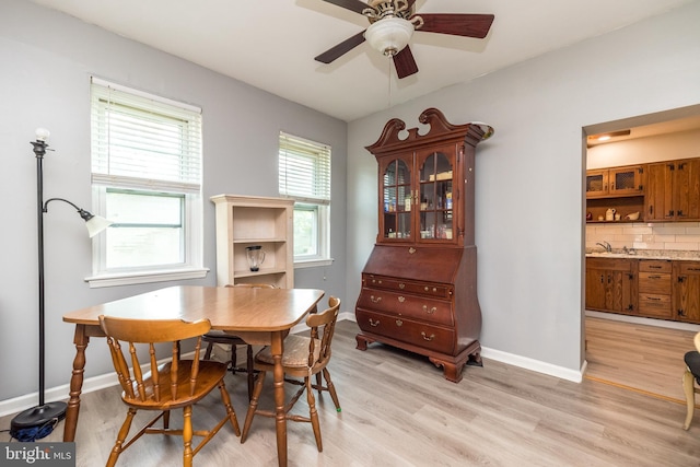 dining space featuring a ceiling fan, light wood-type flooring, and baseboards