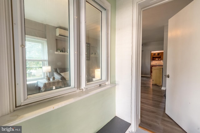 hallway featuring wood-type flooring and an AC wall unit