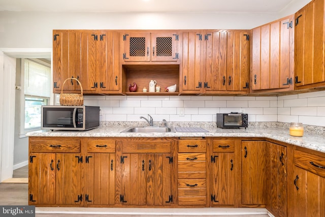 kitchen with backsplash, stainless steel microwave, open shelves, and a sink