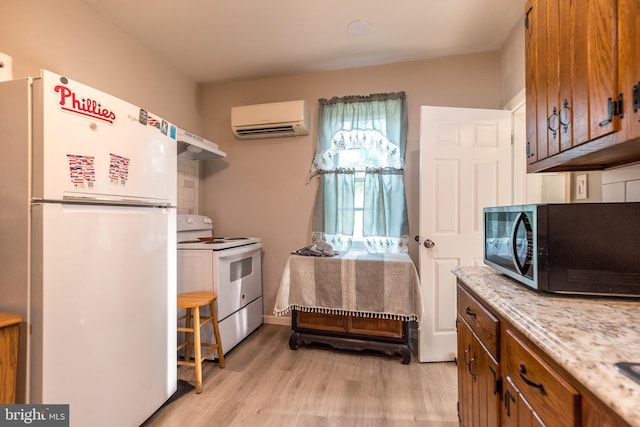 kitchen with white appliances, light countertops, a wall mounted AC, light wood-type flooring, and brown cabinetry