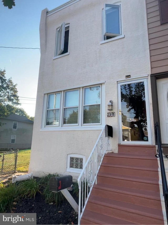 property entrance featuring fence and stucco siding