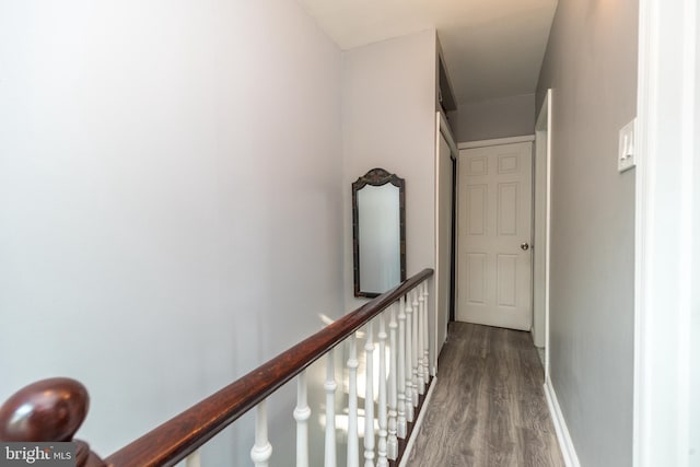 corridor featuring wood finished floors, an upstairs landing, and baseboards