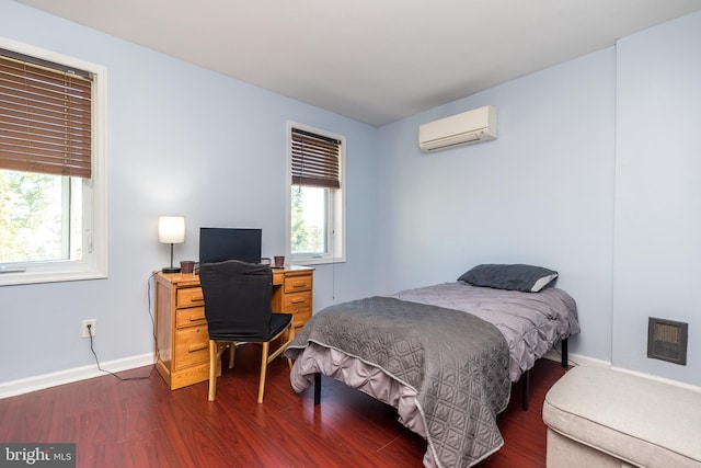 bedroom with dark wood-type flooring, baseboards, and a wall mounted AC