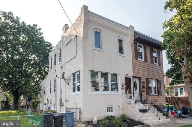 view of front facade featuring central air condition unit, fence, and stucco siding