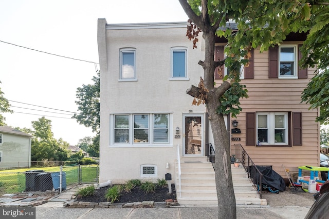 townhome / multi-family property with cooling unit, fence, and stucco siding