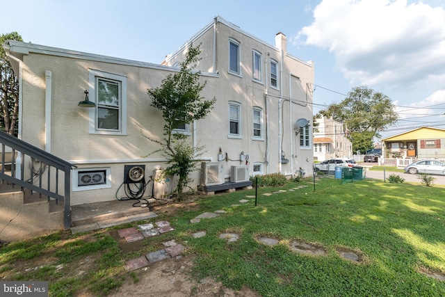 exterior space with fence, a lawn, and stucco siding