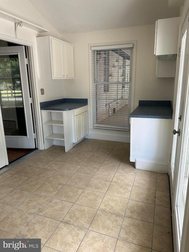 kitchen featuring white cabinetry, light tile patterned floors, and vaulted ceiling