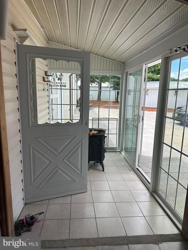 doorway to outside with a wood stove and light tile patterned flooring