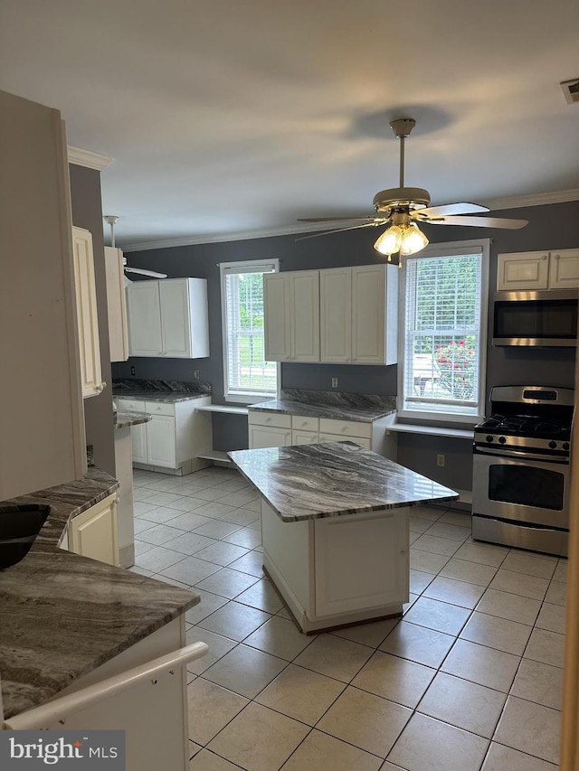 kitchen featuring ceiling fan, a center island, light tile patterned flooring, white cabinetry, and stainless steel appliances