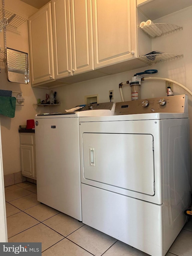 laundry area featuring cabinets, independent washer and dryer, and light tile patterned flooring