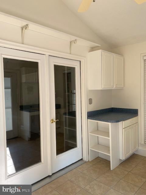 kitchen featuring french doors, vaulted ceiling, and white cabinetry