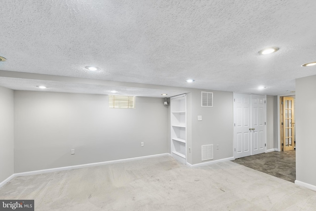 basement featuring light colored carpet and a textured ceiling