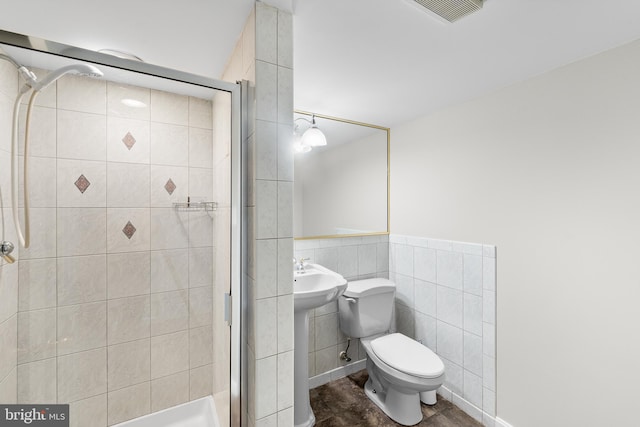 bathroom featuring tile walls, sink, toilet, and a shower with door