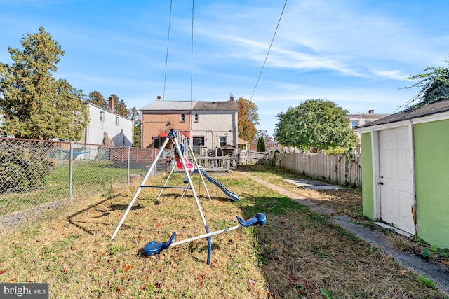 back of property with a playground and a storage shed