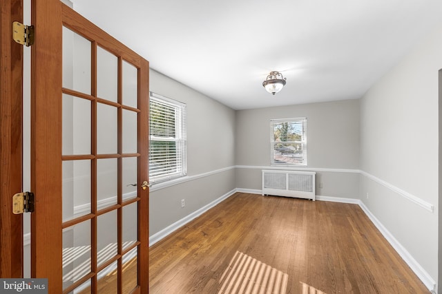 spare room with radiator heating unit and wood-type flooring