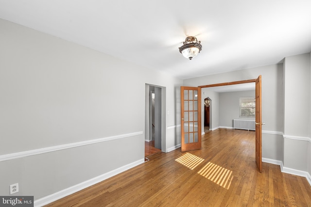 empty room featuring radiator, wood-type flooring, and french doors