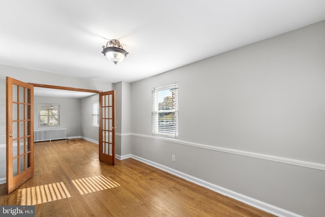 empty room with radiator, light wood-type flooring, and french doors